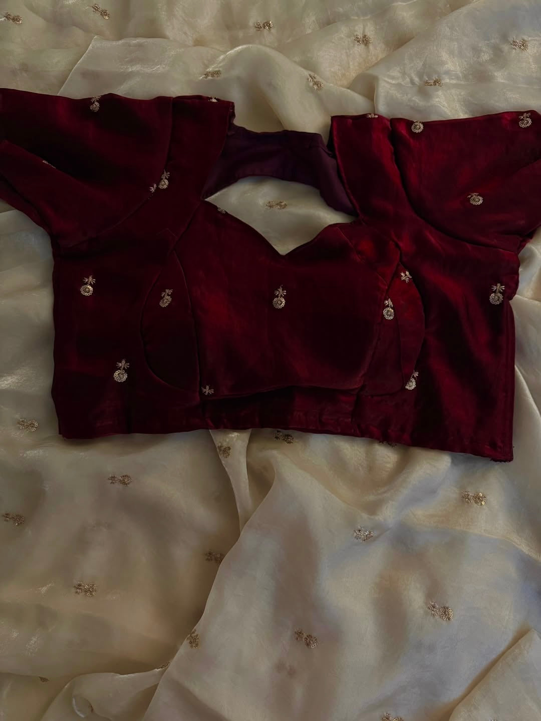 A Soft Beige Color Stardust Satin Saree Dual Shaded Sequins Jari Butti Work Allover the saree paired with Deep Maroon Color Sequins work Blouse