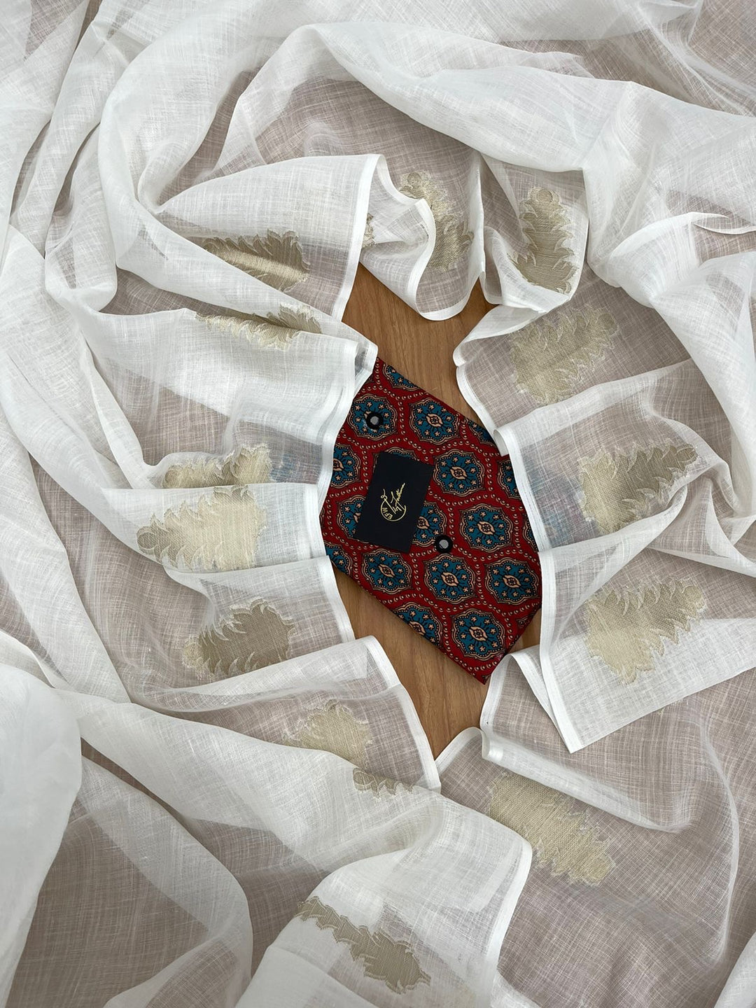 White LINEN Saree, featuring beautiful zari woven leaf design...pallu is adorned with cotton tassels...blouse is made of linen fabric with ajrakh style prints and foil mirror work