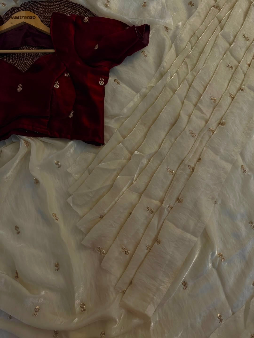 A Soft Beige Color Stardust Satin Saree Dual Shaded Sequins Jari Butti Work Allover the saree paired with Deep Maroon Color Sequins work Blouse