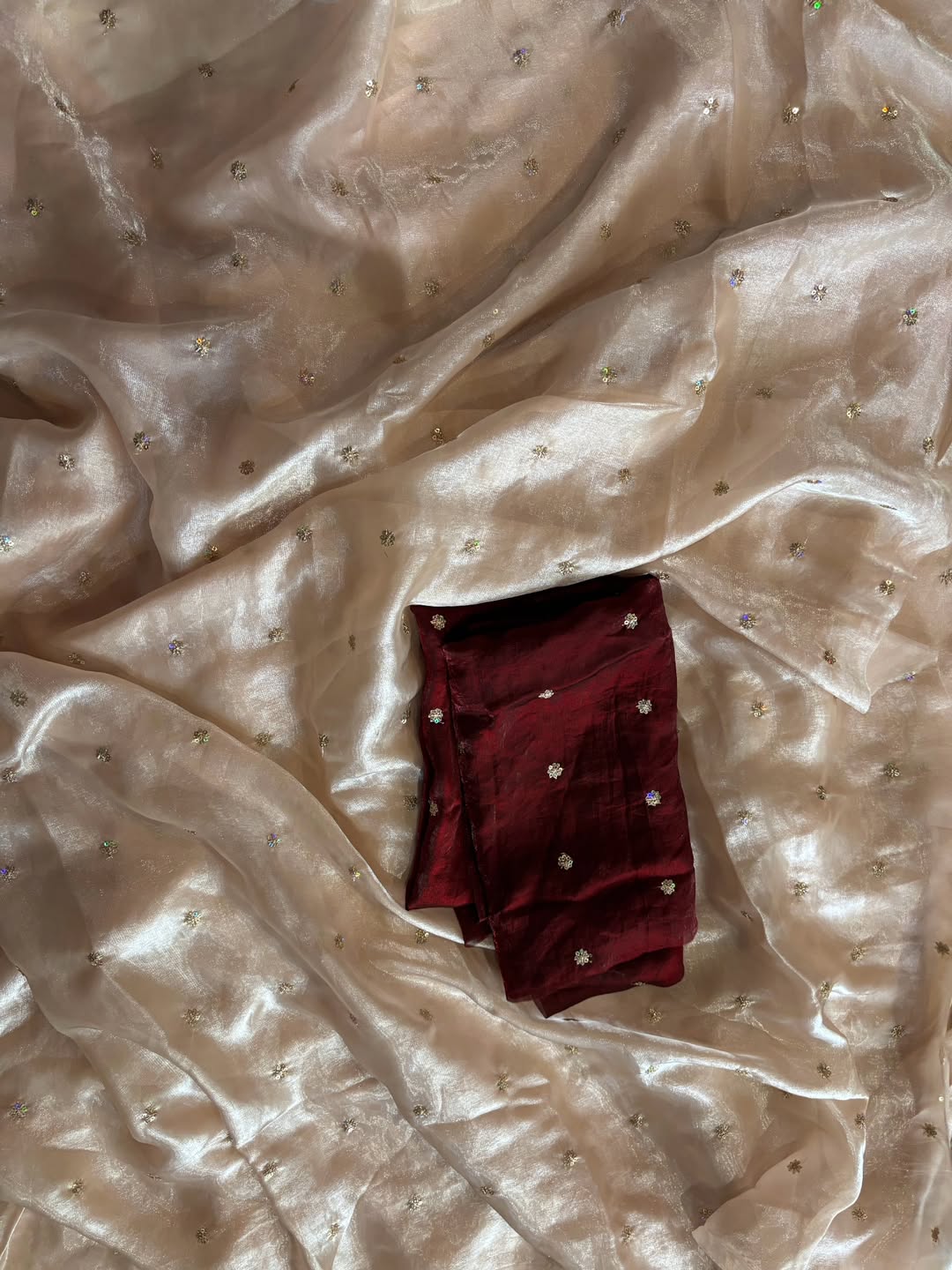 A Soft Beige Color Stardust Satin Saree Dual Shaded Sequins Jari Butti Work Allover the saree paired with Deep Maroon Color Sequins work Blouse