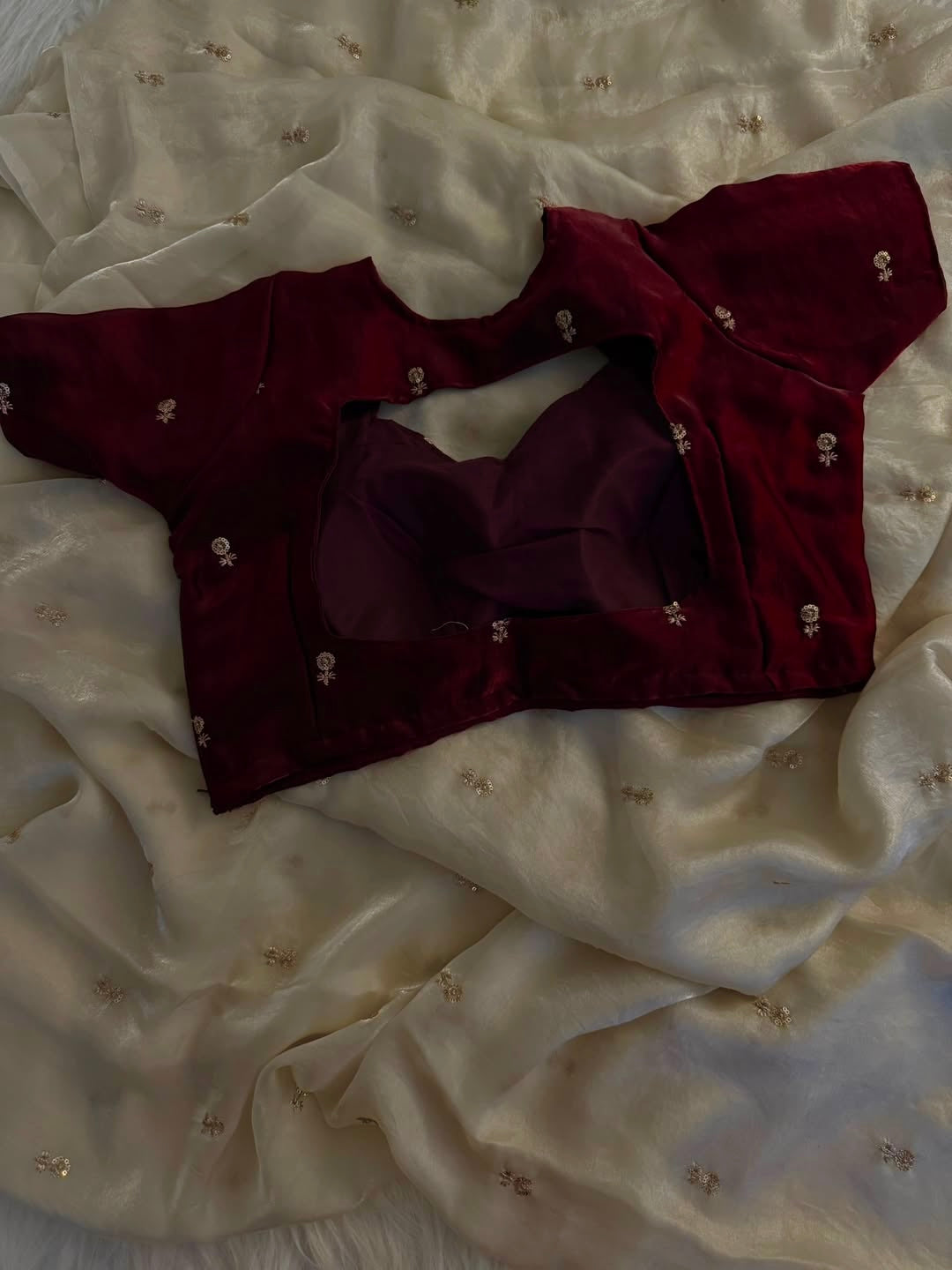 A Soft Beige Color Stardust Satin Saree Dual Shaded Sequins Jari Butti Work Allover the saree paired with Deep Maroon Color Sequins work Blouse